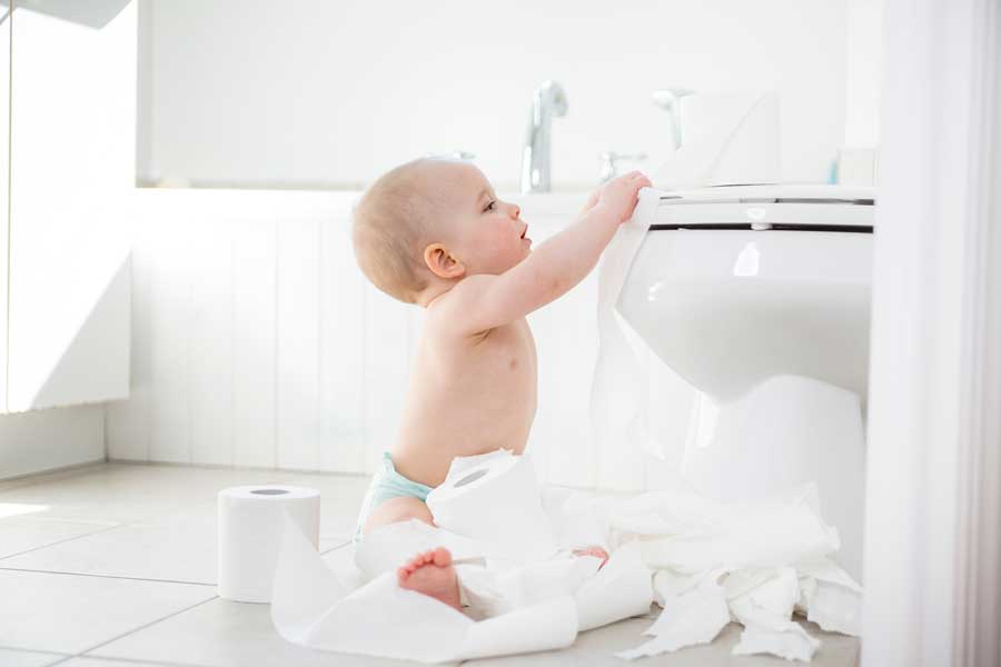 A baby playing with toilet paper