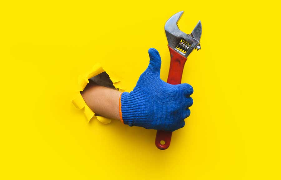A hand holding a wrench giving a thumbs up