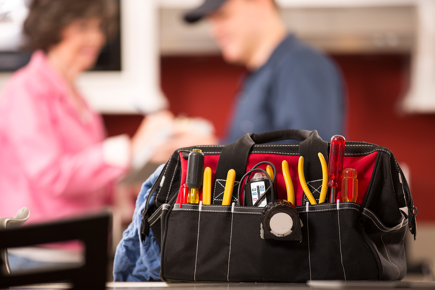 A tool bag with a technician speaking with a client in the background